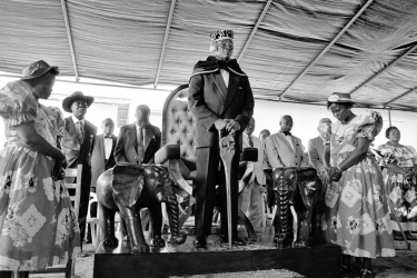 Mitô Honoré Feliciano Julião de Souza, o Chachá VIII, diante do seu trono, com o cetro que simboliza o seu poder. Este traz no punho a representação de um elefante, símbolo do Chachá, que está reproduzido nas duas esculturas em madeira ao lado do trono. Duas jovens da família, a carater, colocaram-se uma de cada lado diante do trono, como damas de honra. Elas foram escolhidas porque são gêmeas, o que significa muito para os africanos. - 7 de outubro de 1995 - Singbomey, Uidá, Benim